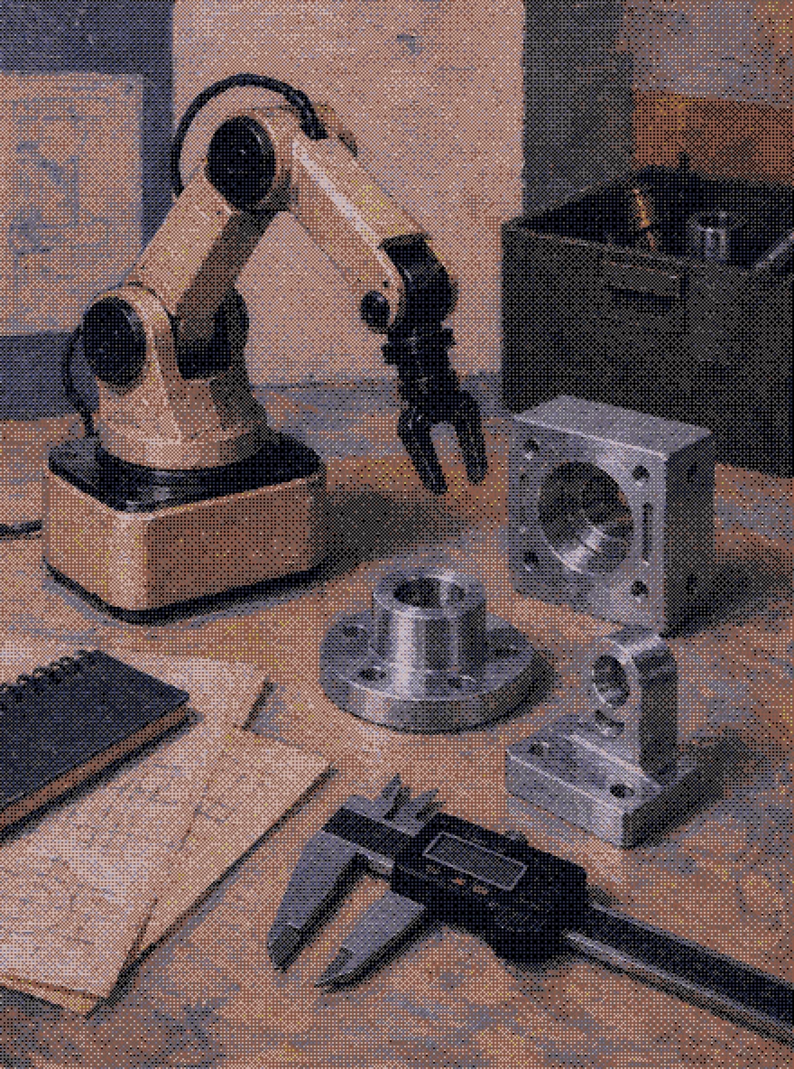 a small robot arm, machined steel parts and calipers laid out on a workbench